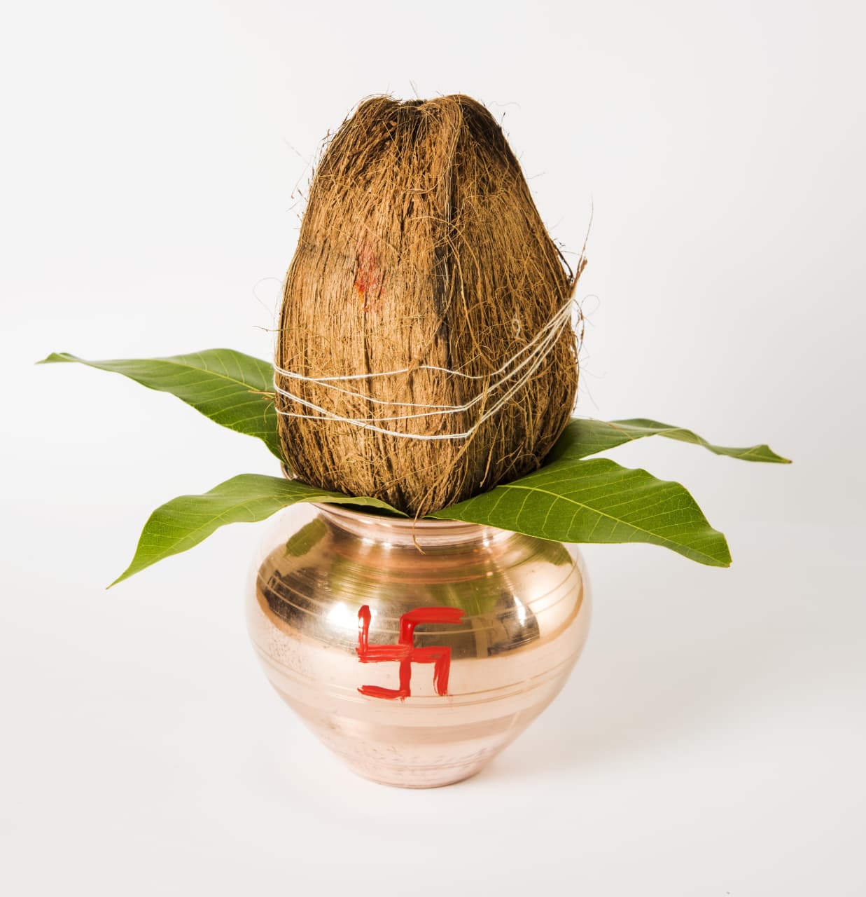 Coconut tied to a copper pot with a Swastika symbol on a white background